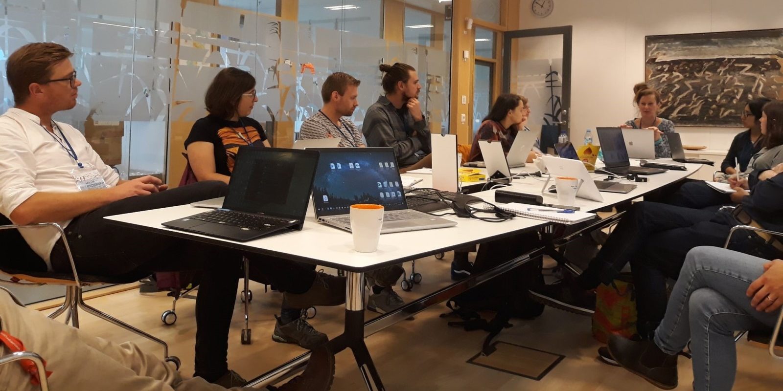 A group of people working together on laptops around a table in a room.