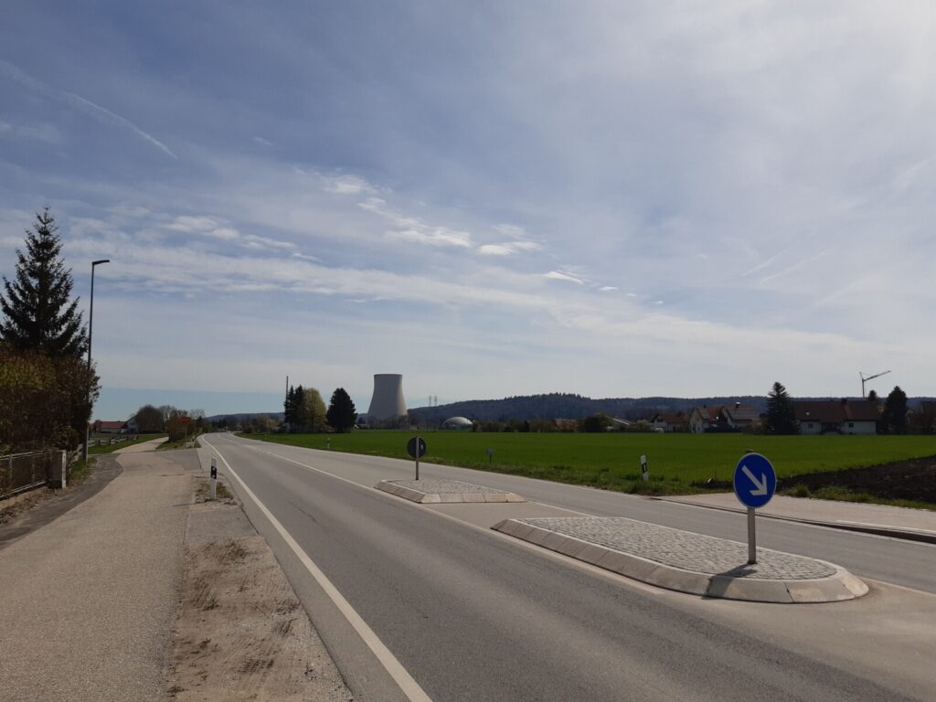 A photograph of a road with the nuclear power plant Isar 2 at the horizon. 
