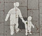 White print on pavement with parent holding kid by the hand