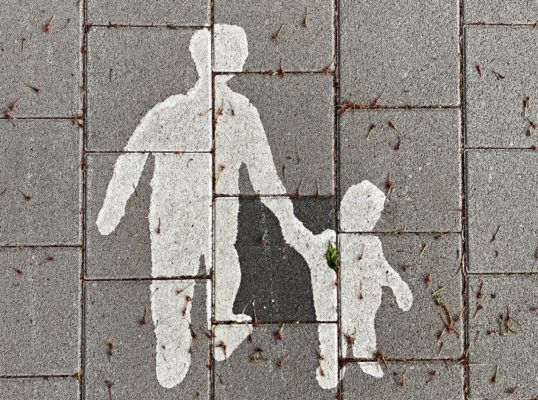 White print on pavement with parent holding kid by the hand
