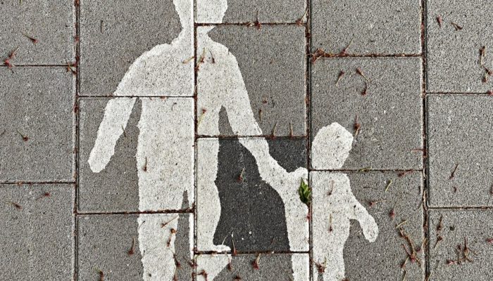 White print on pavement with parent holding kid by the hand