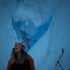 Women inside ice cave looks up in amazement.