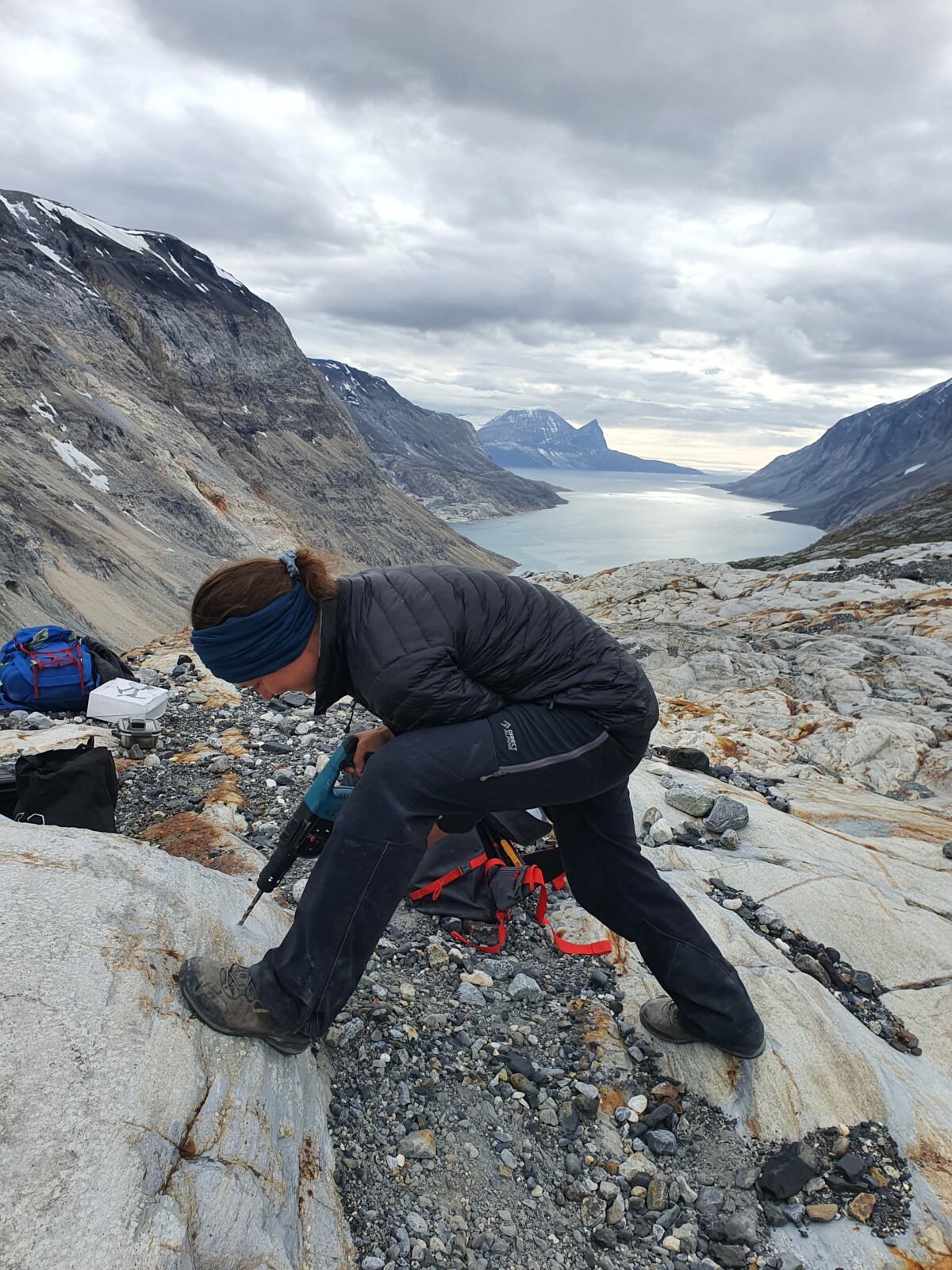 A female scientist drilling in to a rocky outcrop to install a time lapse camera. 