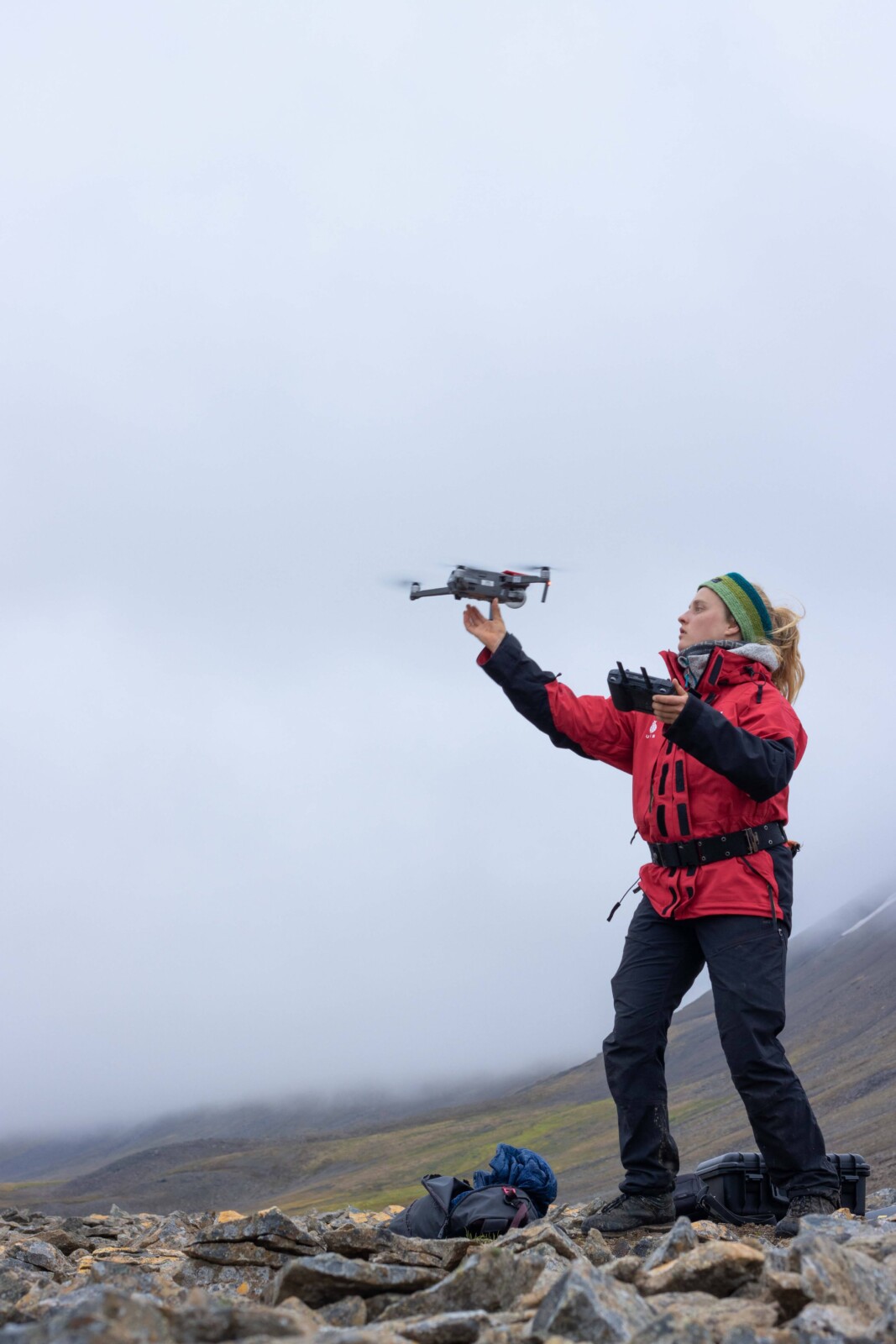 a female scientist flying a drone on a rocky landscape