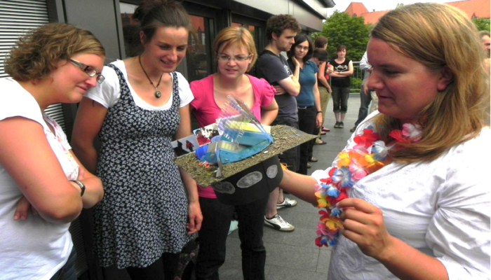 A group of people standing around a person holding a decorated hat in their hand.