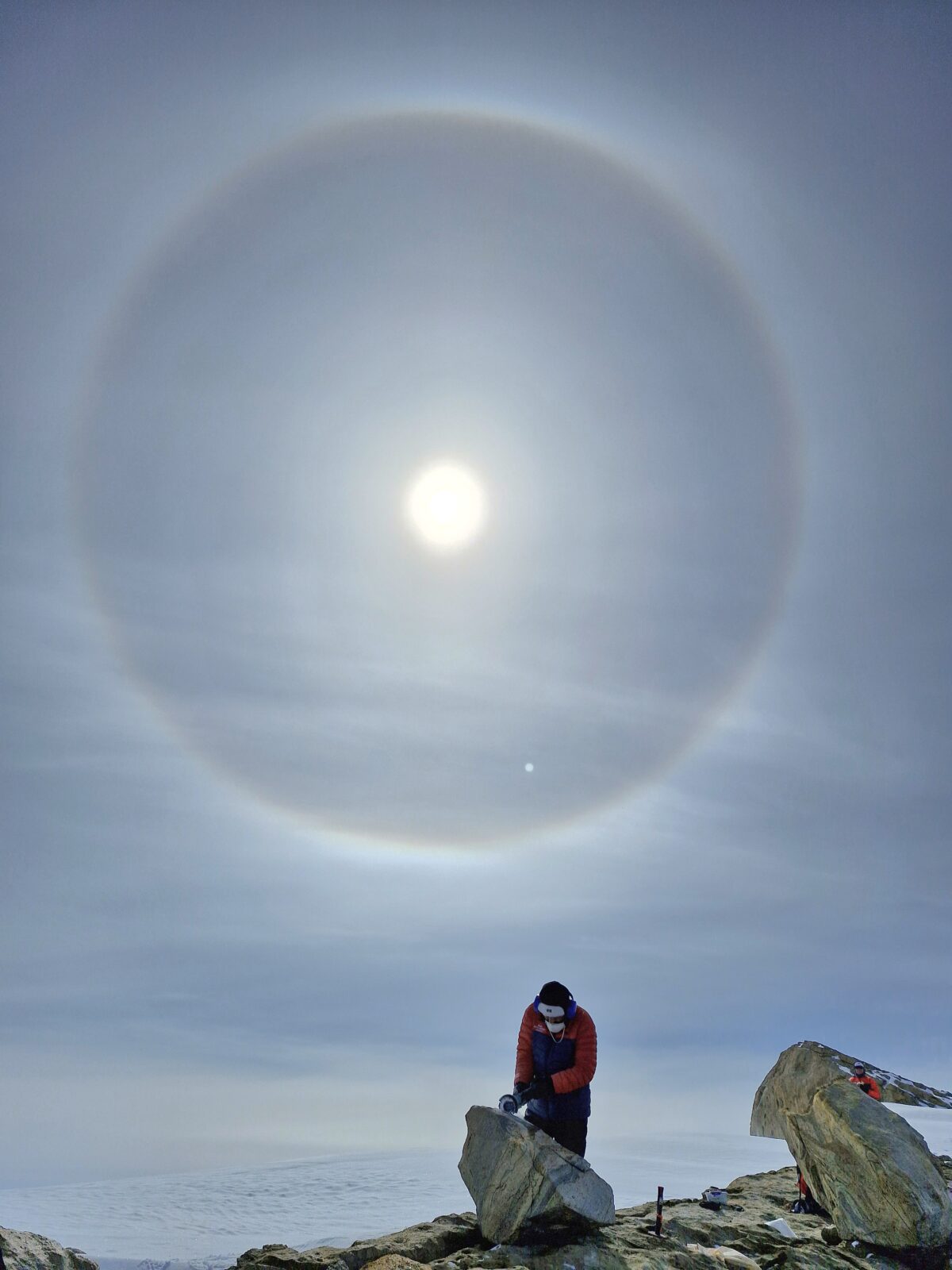 Scientis collecting rocks with a sun dog in the sky