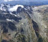 Aerial image showing the climate change impact on small glaciers in the central Greater Caucasus, Georgia. Slopes are extensive deposits of moraines and loose rock debris, left behind by retreating glaciers. A small glacial lake (near the center-bottom of the image) fed by meltwater from the surrounding ice and snow was developed after glacier retreat [Credit: Levan Tielidze].