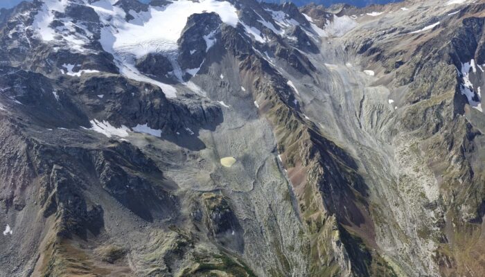 Aerial image showing the climate change impact on small glaciers in the central Greater Caucasus, Georgia. Slopes are extensive deposits of moraines and loose rock debris, left behind by retreating glaciers. A small glacial lake (near the center-bottom of the image) fed by meltwater from the surrounding ice and snow was developed after glacier retreat [Credit: Levan Tielidze].