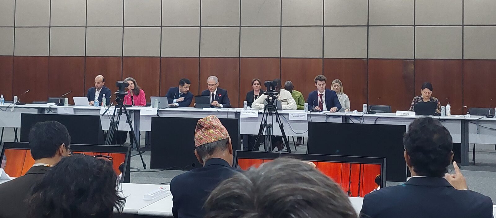 a board of 6 individuals with cameras and media filming them whilst they answer questions from the public.