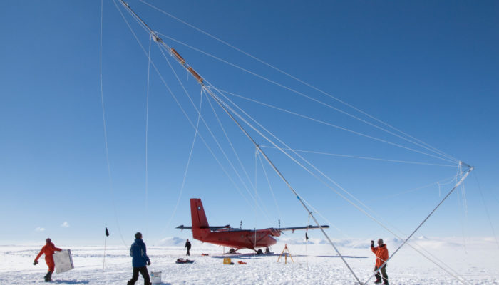 A plane and several researchers on the ice in Antarctica.
