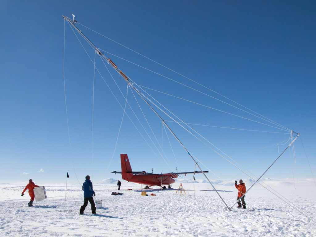A plane and several researchers on the ice in Antarctica.