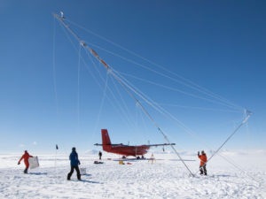 A plane and several researchers on the ice in Antarctica.