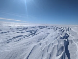 Wavy ice feature in front of wide blue sky.