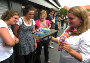 A group of people standing around a person holding a decorated hat in their hand.