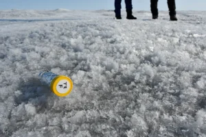 surface of ice sheet with small (pencil-sized) test tube in foreground