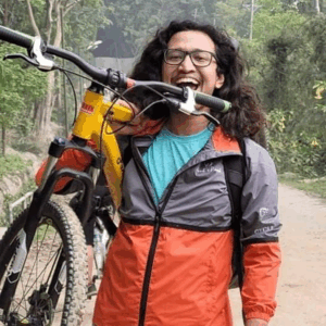 Amin out in nature, carrying a bike, laughing at the camera