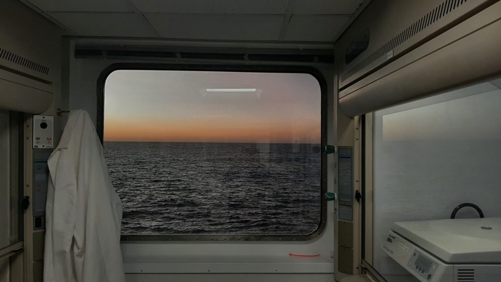 Photo of a pre dawn horizon taken through a window on a ship