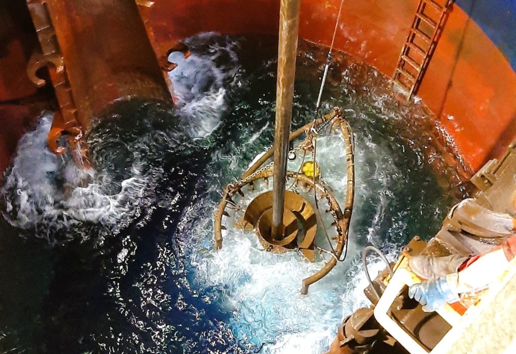 Photo of the drill string descending through the moon pool of the ship into the sea