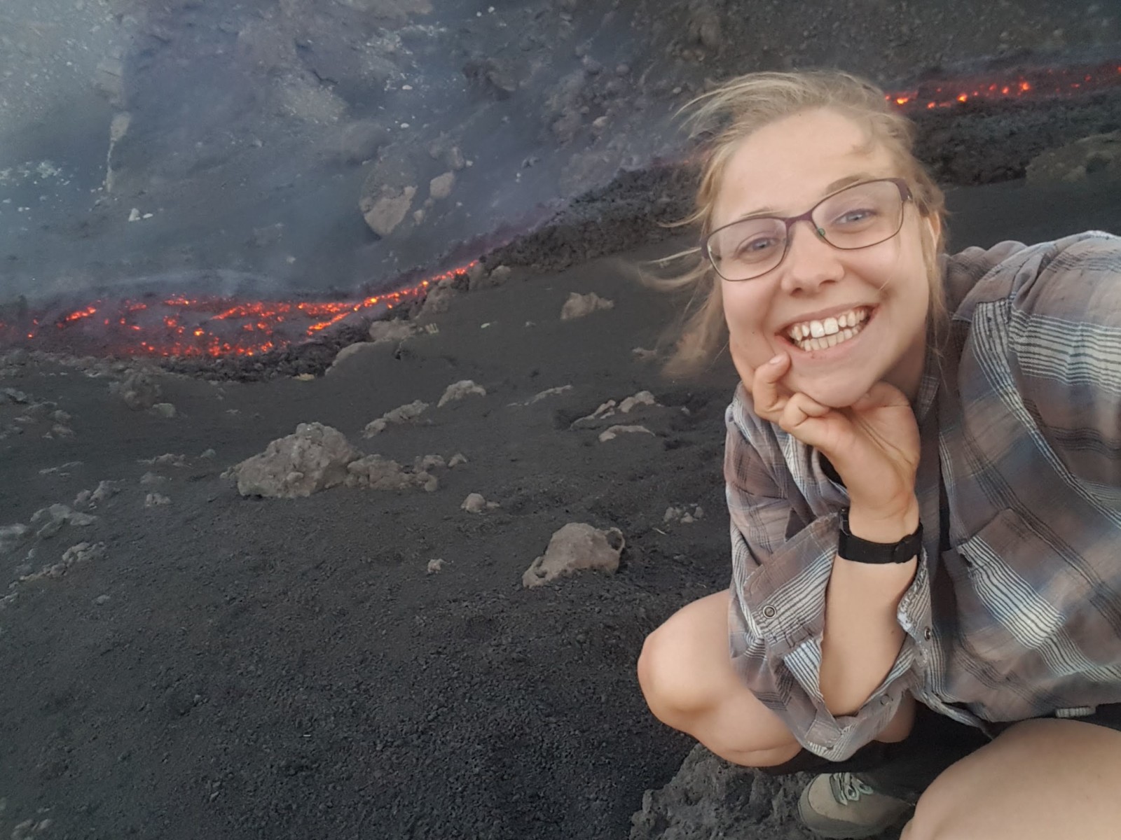 A picture of Corin Jorgenson on the field, close to a runny lava flow on Mt. Etna, 2022