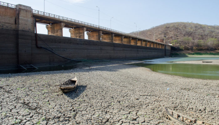 A dam, an almost empty water reservoir and a small abandoned boat