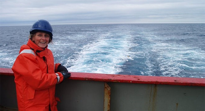 Karen smiles on the left by the ship railing, with the open ocean behind