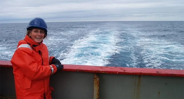 Karen smiles on the left by the ship railing, with the open ocean behind