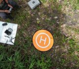 This image shows a drone operator guiding a drone to its landing spot.