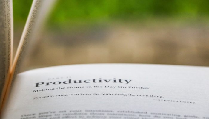 Photo from the page of a book, with an out of focus green background. The text on the page reads: 'Productivity, making the hours in the day go further. The main thing is to keep the main thing the main thing - Steven Covey'.