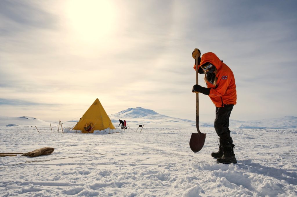 scientist holding shovel standing on ice shelf by Ole Zeising