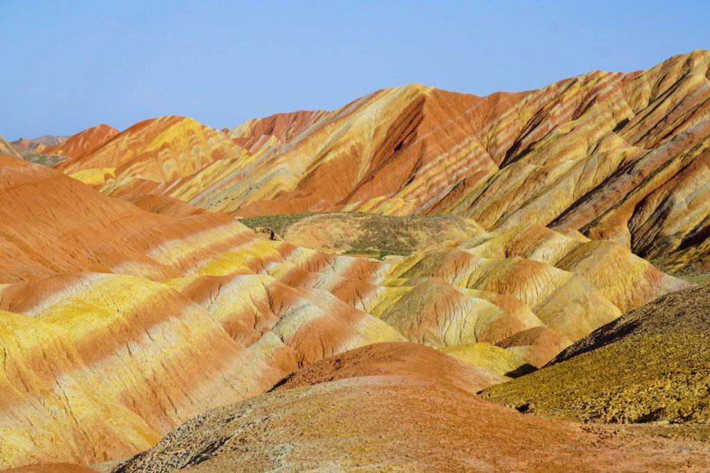 mountains with stripes of yellow, orange and green by Raul-David Serban