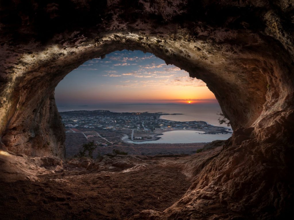 coastal town and sea at sunset framed by a cave by Anastasios Rovithakis