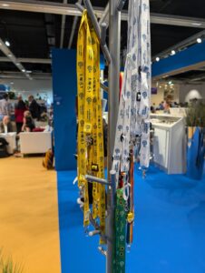 The image shows alternative lanyards being distributed by EDI at the general assembly. Each lanyard can signify different things, allowing people to connect with their communities or convey their needs quickly. 
