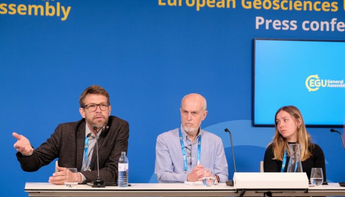 In front of the blue EGU press conference background, Olaf Eisen (left), Robert Larter (middle) and Emma Pearce (right) are engaged in discussion.