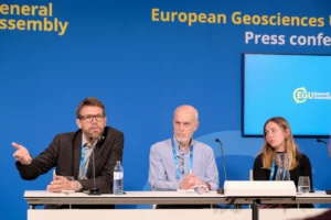 In front of the blue EGU press conference background, Olaf Eisen (left), Robert Larter (middle) and Emma Pearce (right) are engaged in discussion.