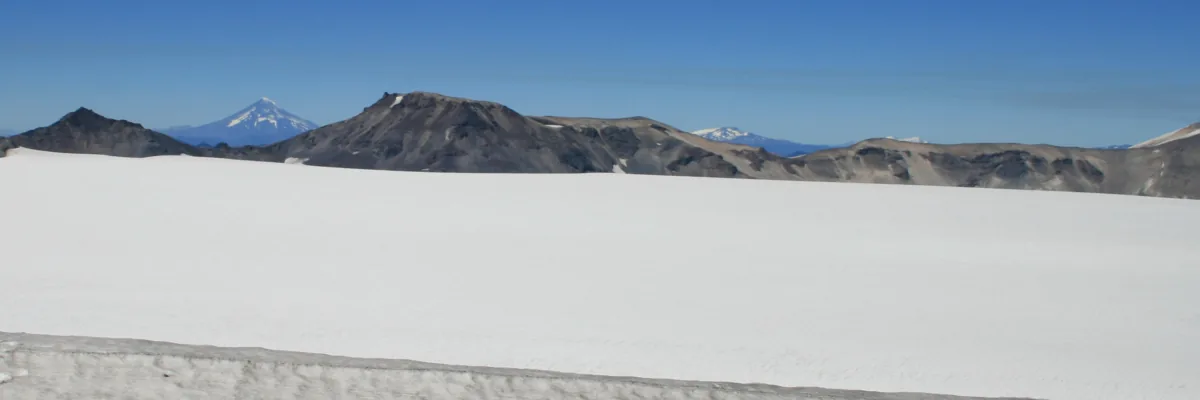 Looking across the ice-filled summit caldera of a volcano to distant peaks