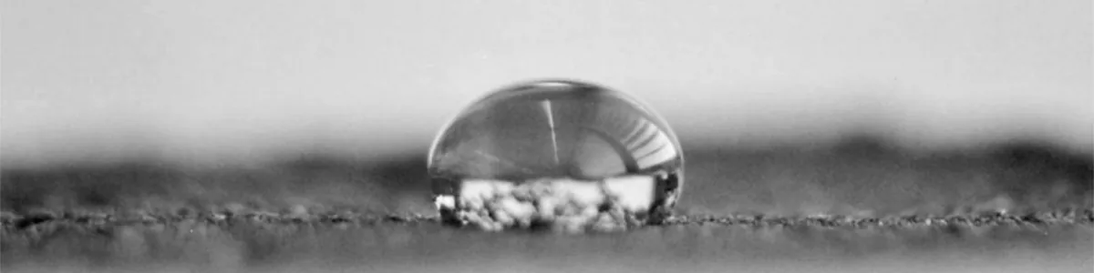 Detail of a photo: Five stacked black-and-white close-ups of a water drop on soil, seen from the side. From top to bottom the clear rounded drop shrinks and darkens into a small dark mound.
