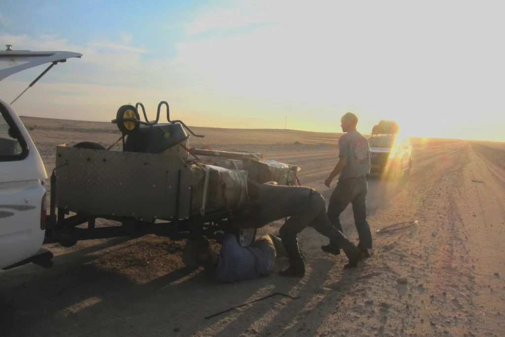 Trailer repair at sunset with a ratchet strap, a jack, and a socket extension. (Credit: A. Dansie)