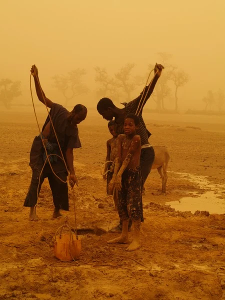 Men and children drawing water for irrigation during a sandstorm. (Credit: Velio Coviello via imaggeo.egu.eu)