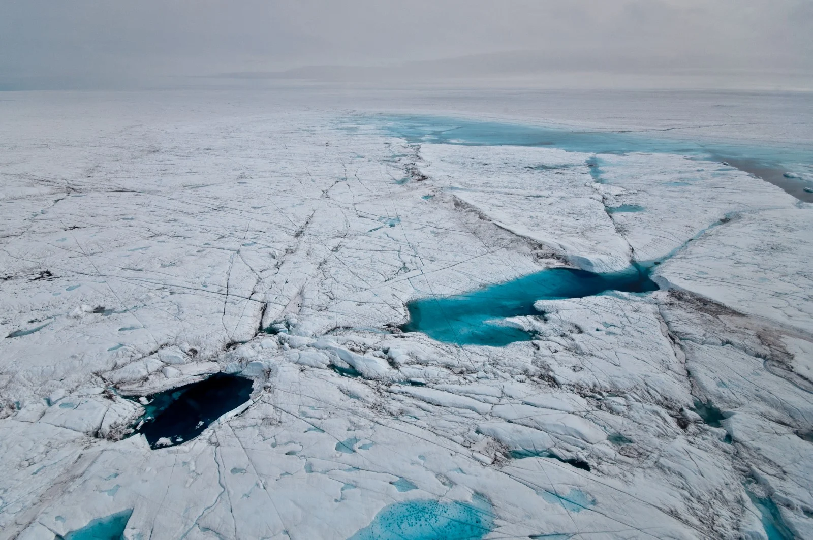 Drained Supraglacial Lake Bed. This lake has drained through the bottom for several years in a row. The large block was initially formed in summer of 2006, but large cracks run through it from subsequent lake drainages. Credit: Ian Joughin (distributed via imaggeo.egu.eu )