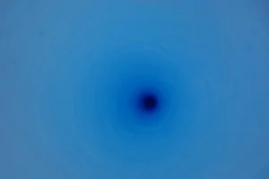 The deep blue colour of the ice is visible looking down the core hole. (Credit: H. Millman)