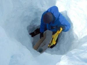 E. Bagshaw testing the range of an ETracer in a 12m borehole at the bottom of a 2m deep snow pit. [Credit: N. B. Karlsson].