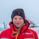 Imagine of person with red jacket and black AWI hat and snow in the background.