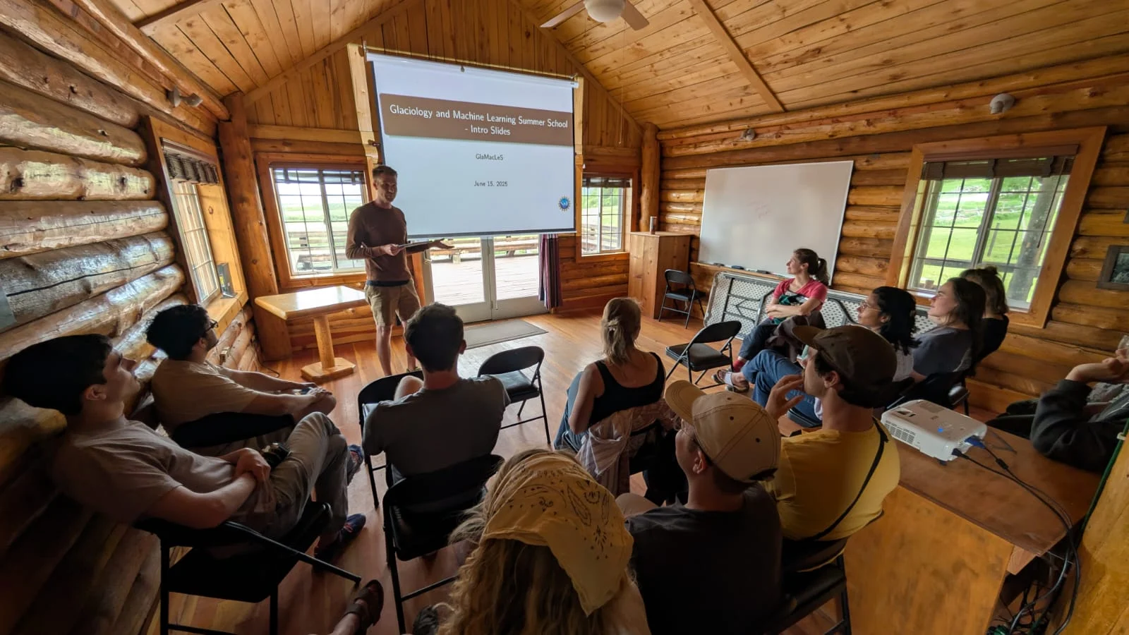 a group of people listening to a presentation inside the small wooden cabin from figure 1. 