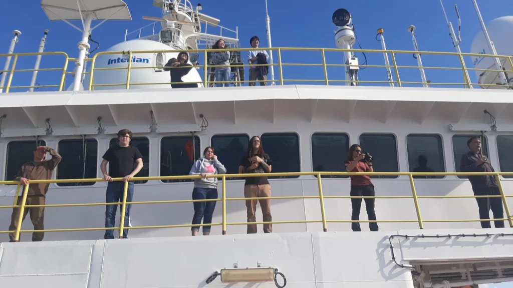 Photo of people standing on the bridge of a ship watching land appear