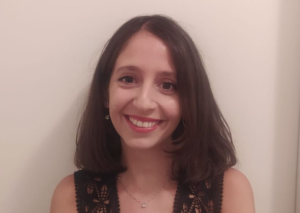 Michaela in front of a white background, smiling at the camera