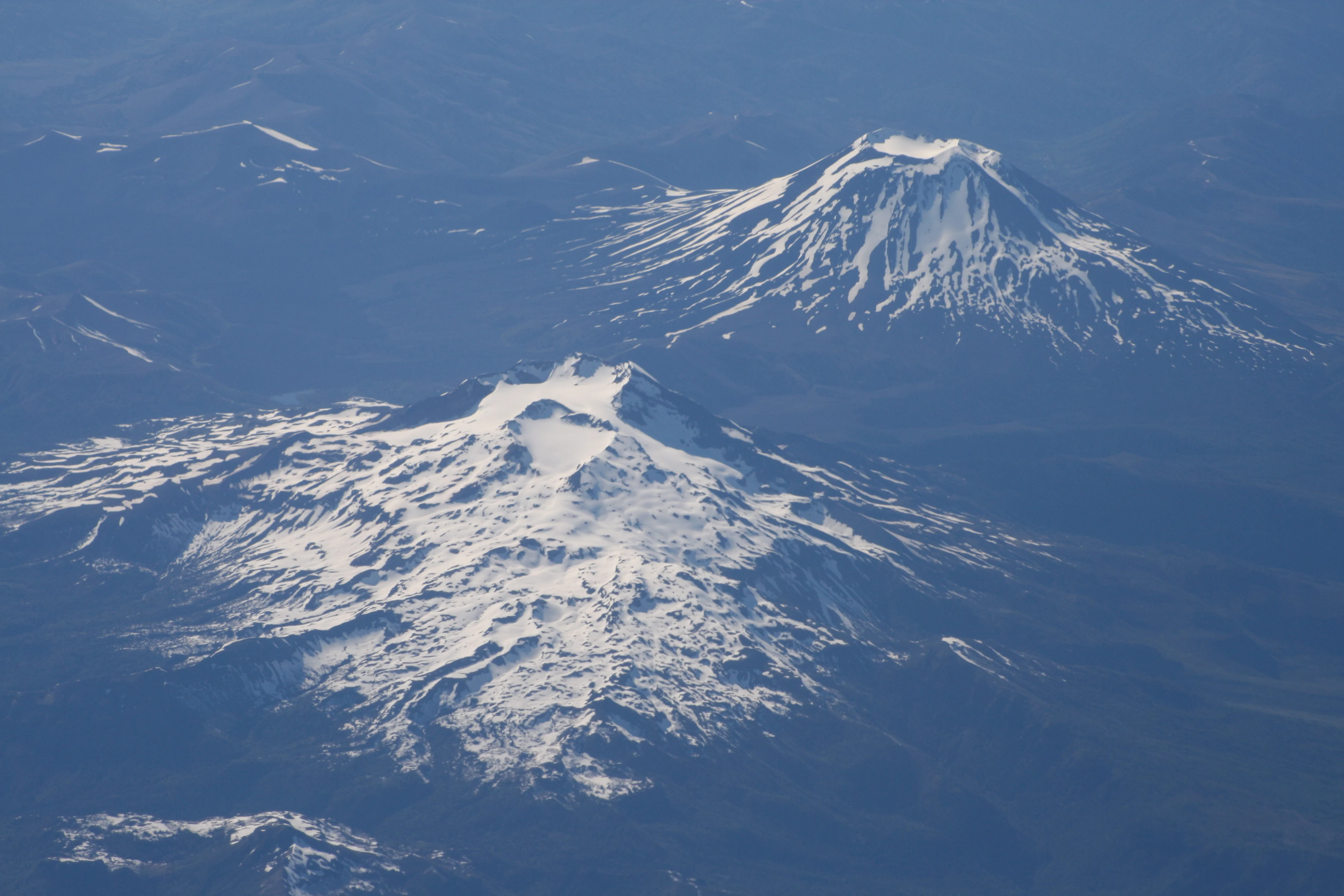 View across the volcanoes of Tolhuaca (or Tolguaca, near ground) and Lonquimay (38.3 S). Both volcanoes are young, but it is not known when Tolhuaca last erupted. Lonquimay last erupted from 1988-1990. 