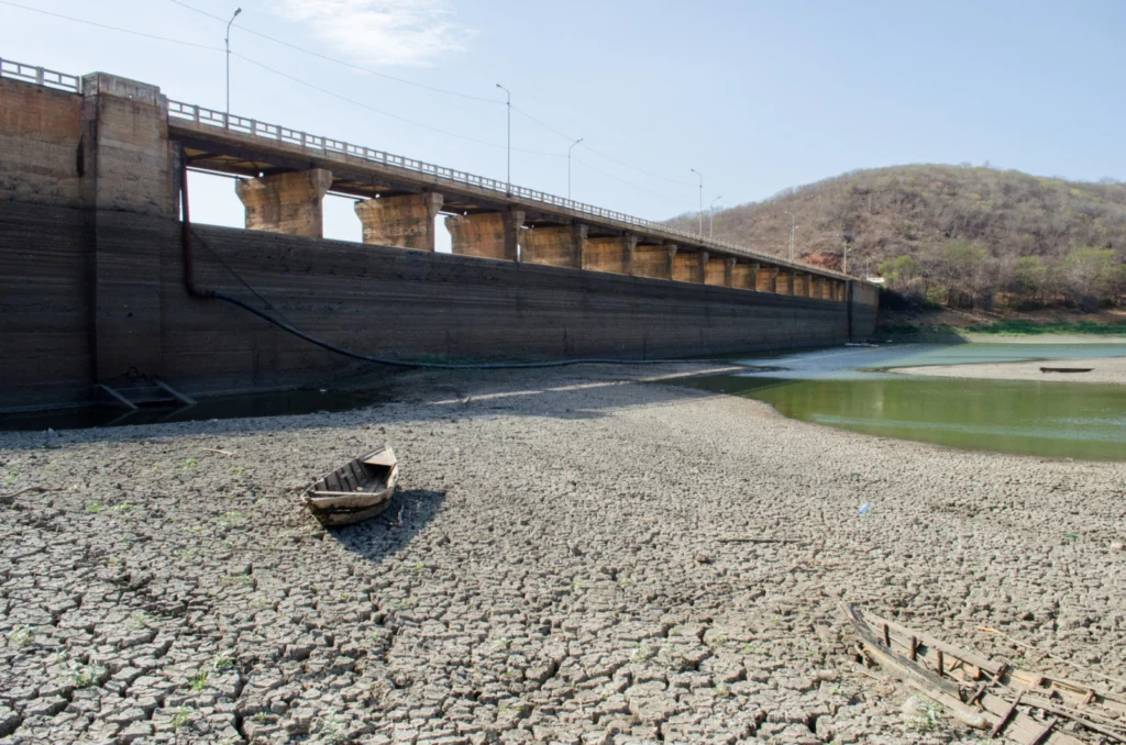 A dam, an almost empty water reservoir and a small abandoned boat
